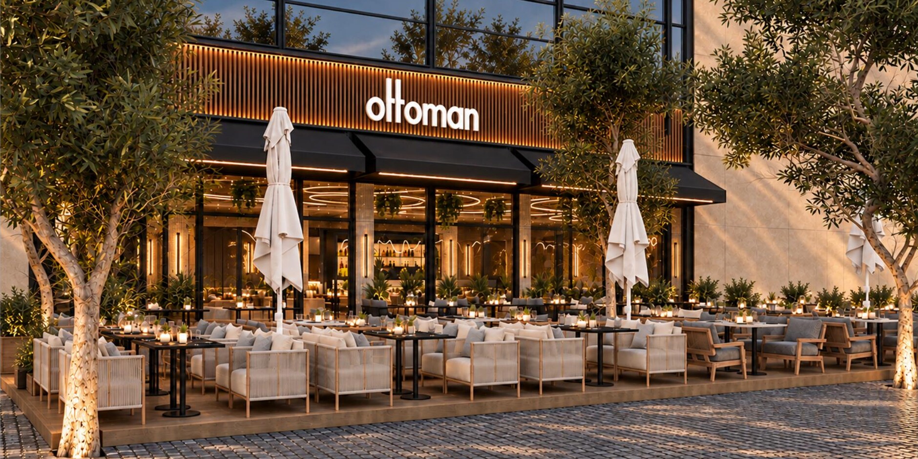 Het terras van Ottoman Amsterdam — loungesets, olijfbomen en sfeerverlichting